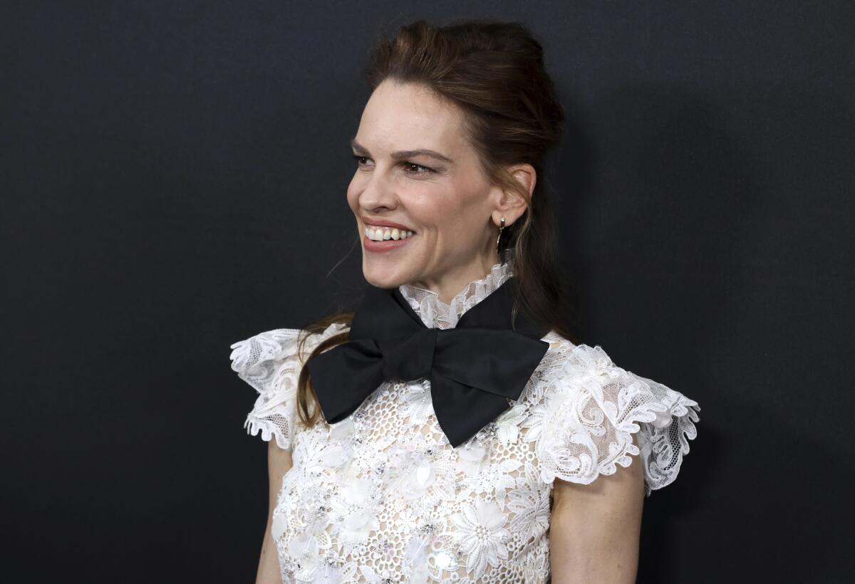 Hilary Swank smiles in white lace top and oversized black bow tie