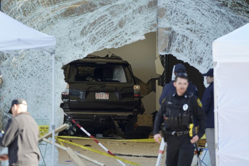 FILE - An SUV rests inside an Apple store behind a large hole in the glass front of the store on Nov. 21, 2022, in Hingham, Mass. The family of a man who was badly hurt when an SUV crashed into an Apple store in Massachusetts, killing one person and injuring 20, sued the company, the driver and the property owners Tuesday, Nov. 29, in one of the first lawsuits filed over the crash. (AP Photo/Steven Senne, File)