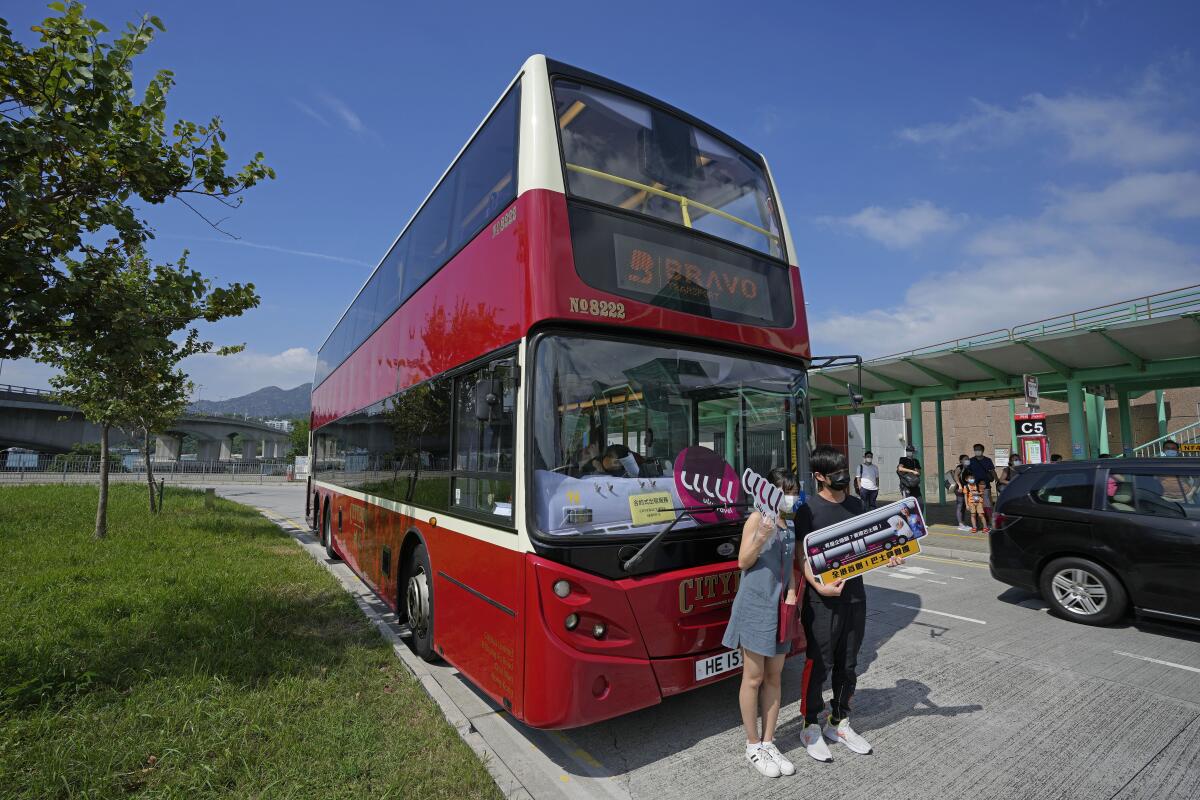 Pasajeros posan para una foro delante de un autobús antes de abordar, en Hong Kong