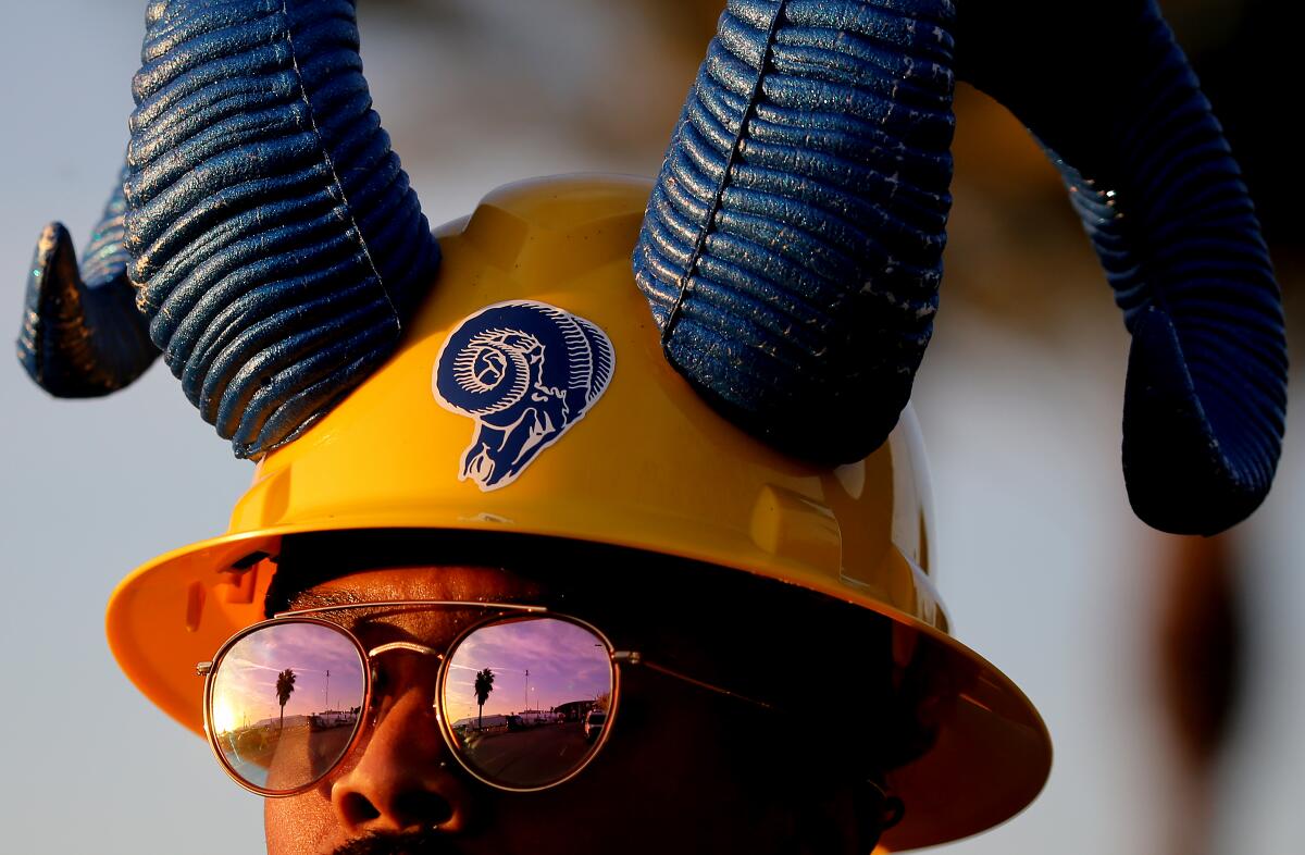 A Rams fan with a yellow hat with blue horns on it