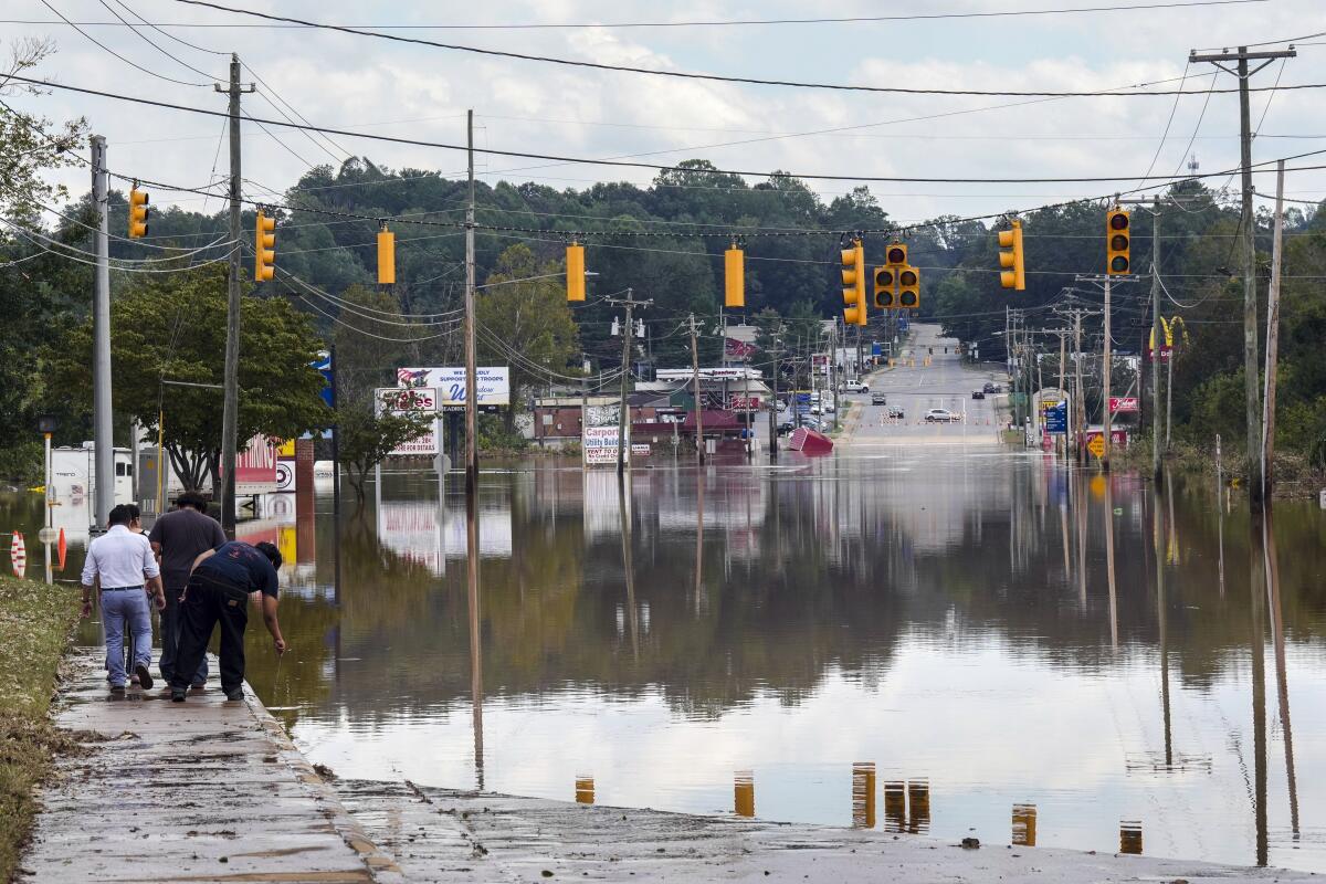 A passerby checks the water depth of a flooded road in Morganton, N.C.