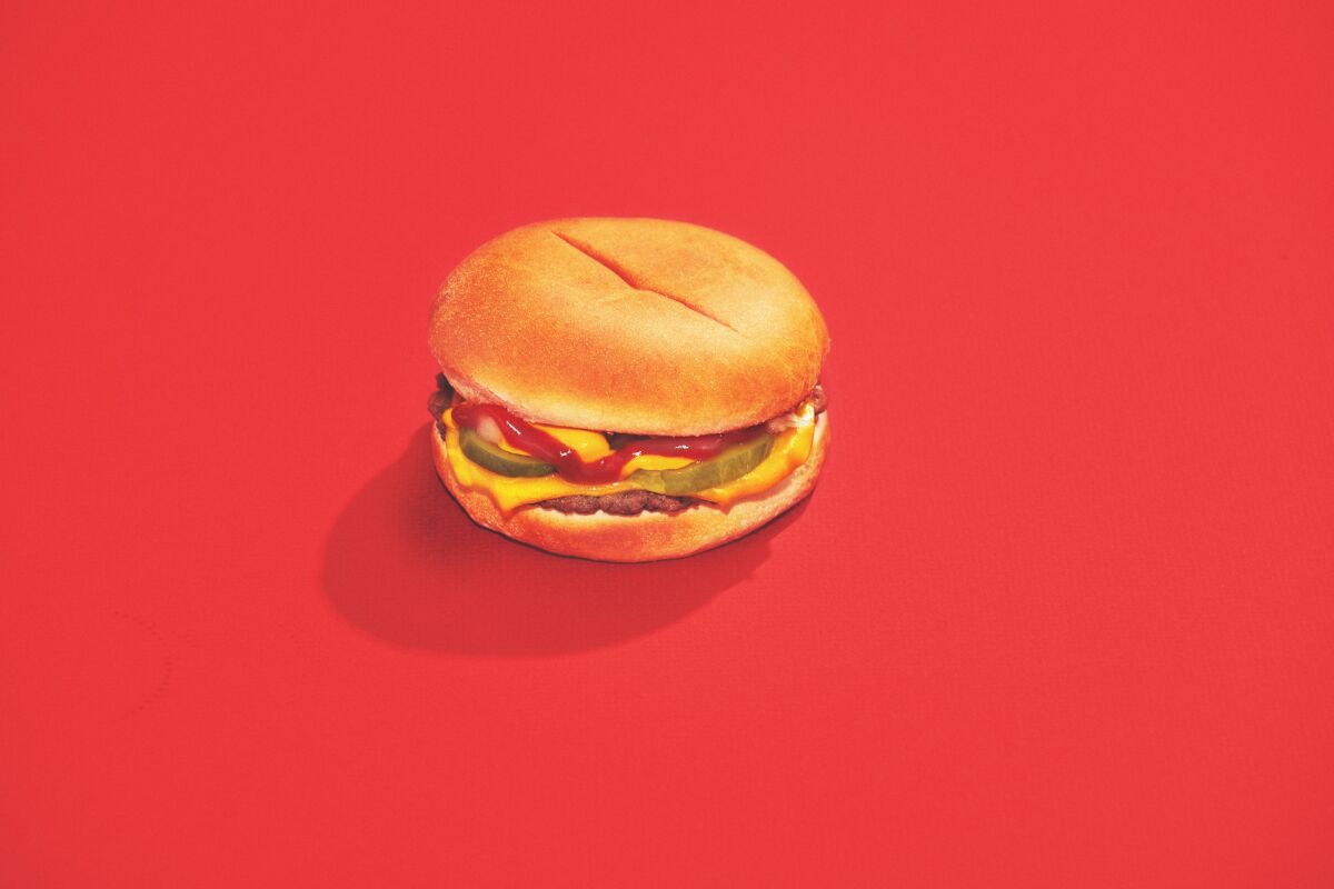A vegan hamburger on a bun photographed on a red background.