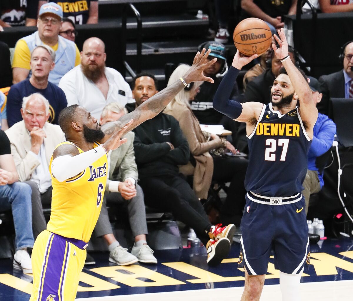 Denver Nuggets guard Jamal Murray shoots a three-point basket while Lakers forward LeBron James defends.