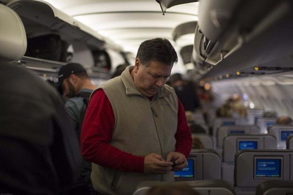 A JetBlue Airways passenger checks his cellphone after landing at Long Beach Airport.