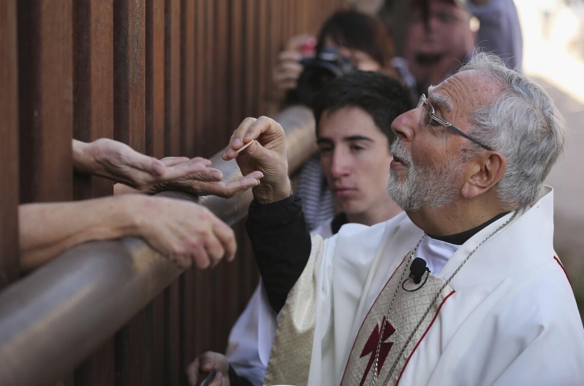 Bishop of Tucson Gerald Kicanas passes communion wafers through to the Mexican side of the U.S.-Mexico border fence during a special “Mass on the Border” on April 1, 2014, in Nogales, Ariz.