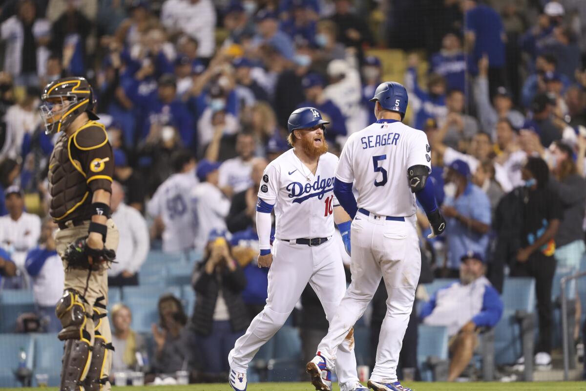 Padres catcher Victor Caratini looks away as Dodgers' Justin Turner and Corey Seager celebrate.