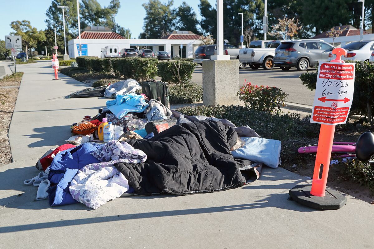 A woman sleeps along the sidewalk in front of the Newport Transportation Center.
