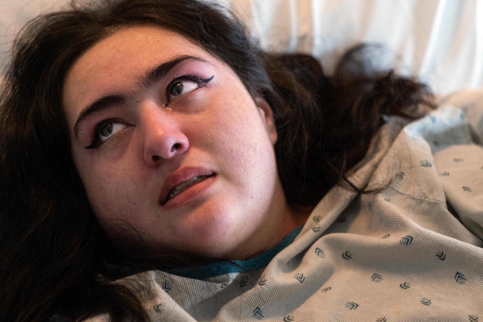 A close-up of a woman in hospital garb lying on a bed