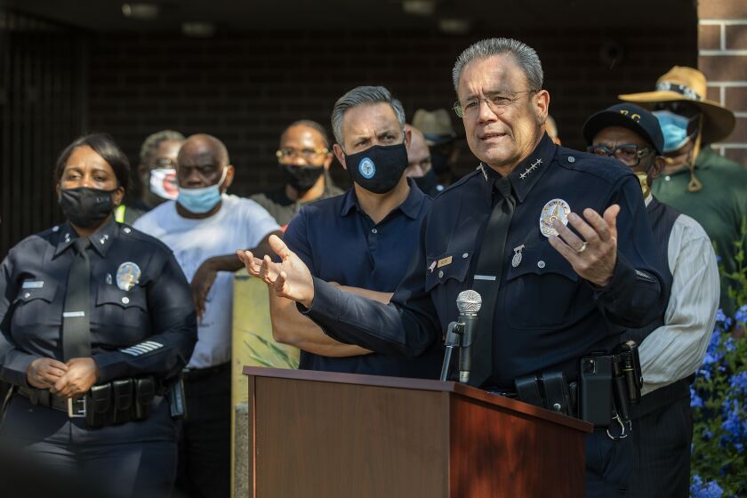 LAPD Police Chief Michel Moore, right, addresses the media outside the Southeast Community Police Station