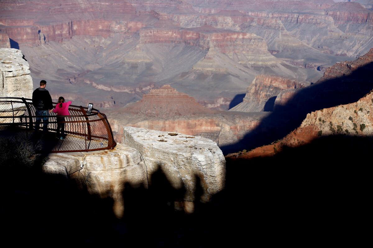 Two people look out at shadows over the Grand Canyon