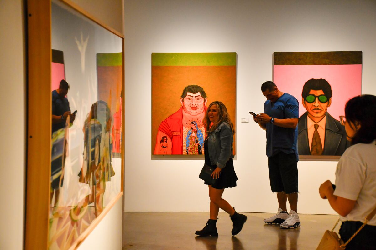 People in an art gallery with colorful portraits hanging on the walls