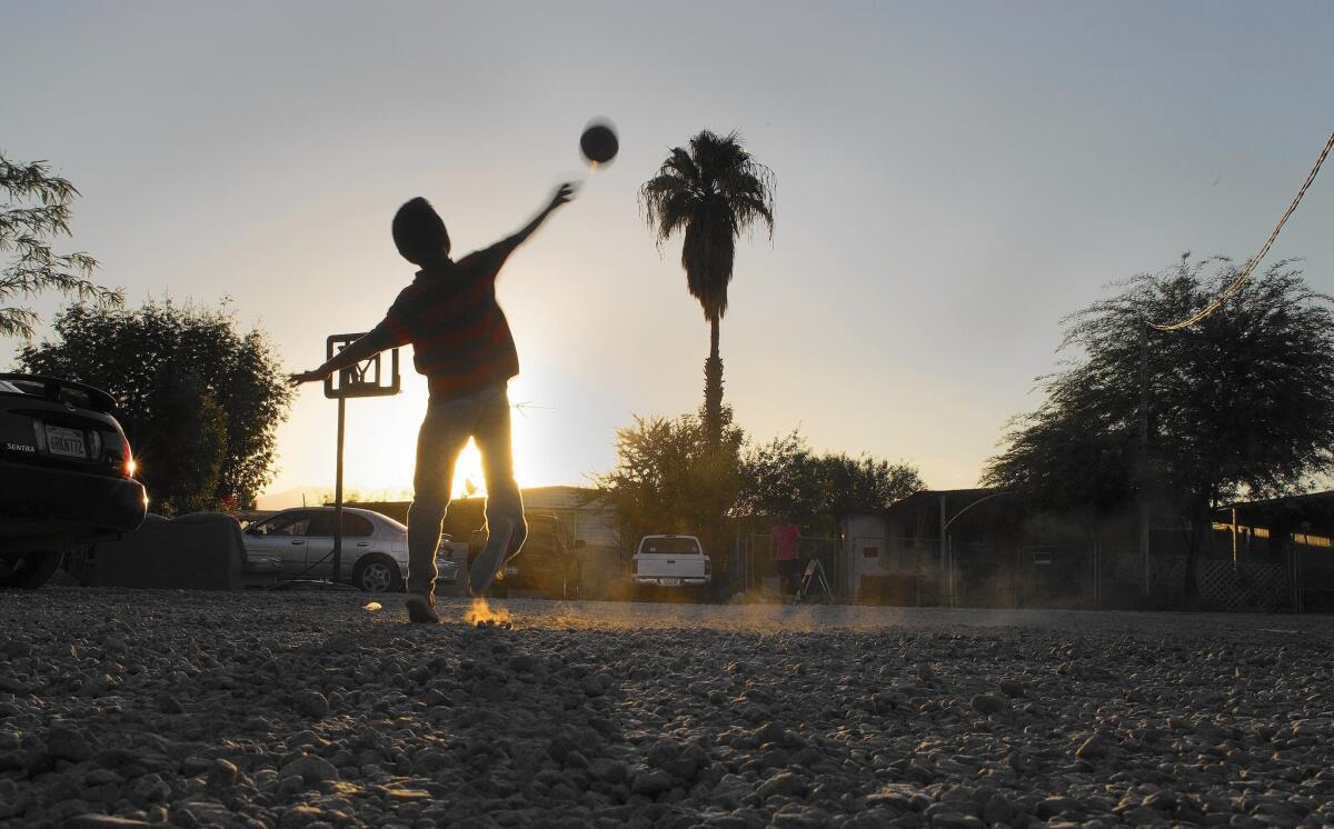 At St. Anthony's trailer park in Mecca, the nonprofit Pueblo Unido stepped in as owner to make improvements, but residents are frustrated with the slow progress. Above, Aaron Gonzalez, 11, tosses a football.