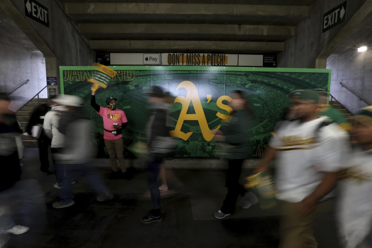 Fans pass an image of the Oakland Athletics team logo at the Oakland Coliseum in April 2022.