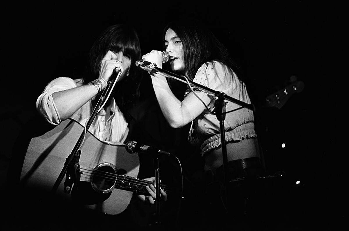 A male and female country singer perform onstage in the 1970s.