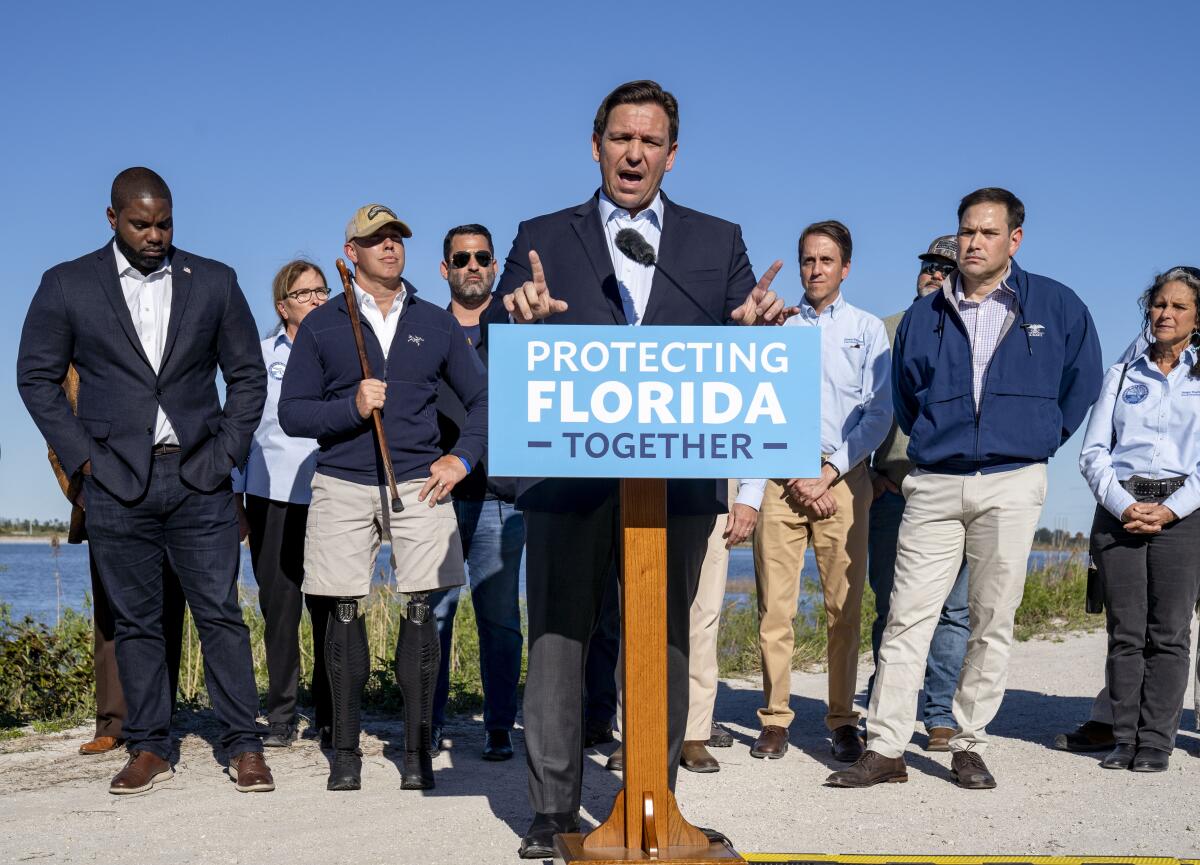 A man at a lectern with eight people behind him 