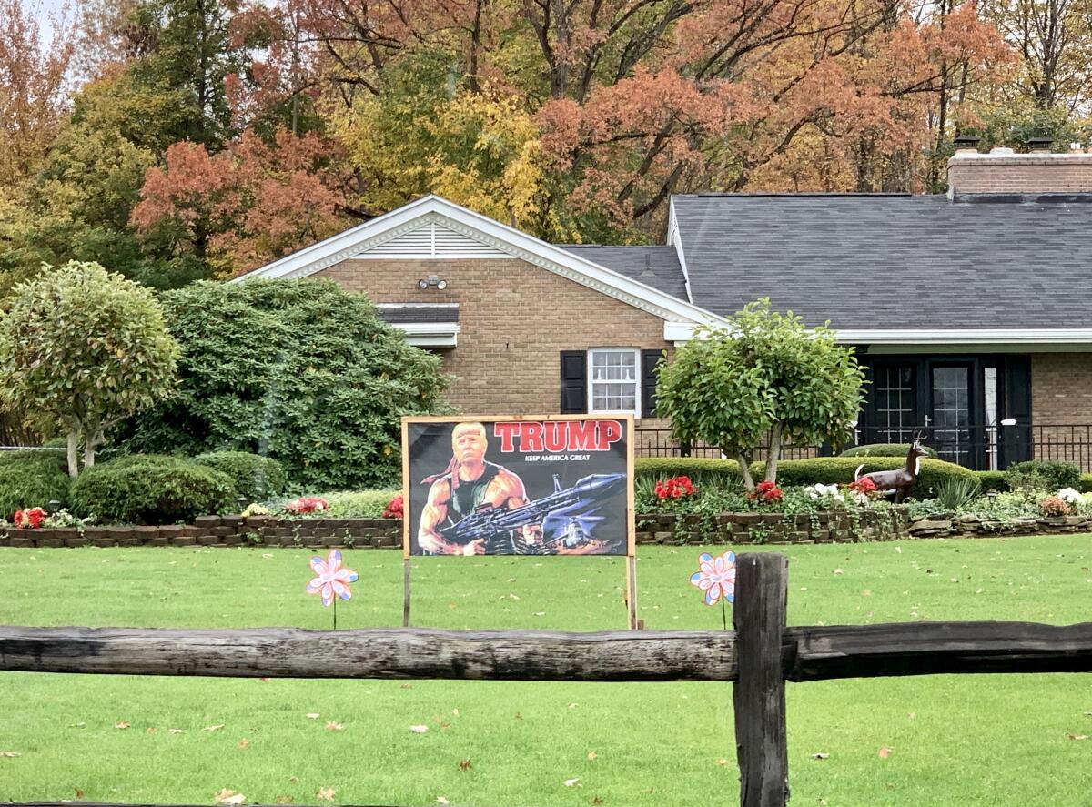 A lawn sign depicts President Trump as Rambo, armed with heavy weapons