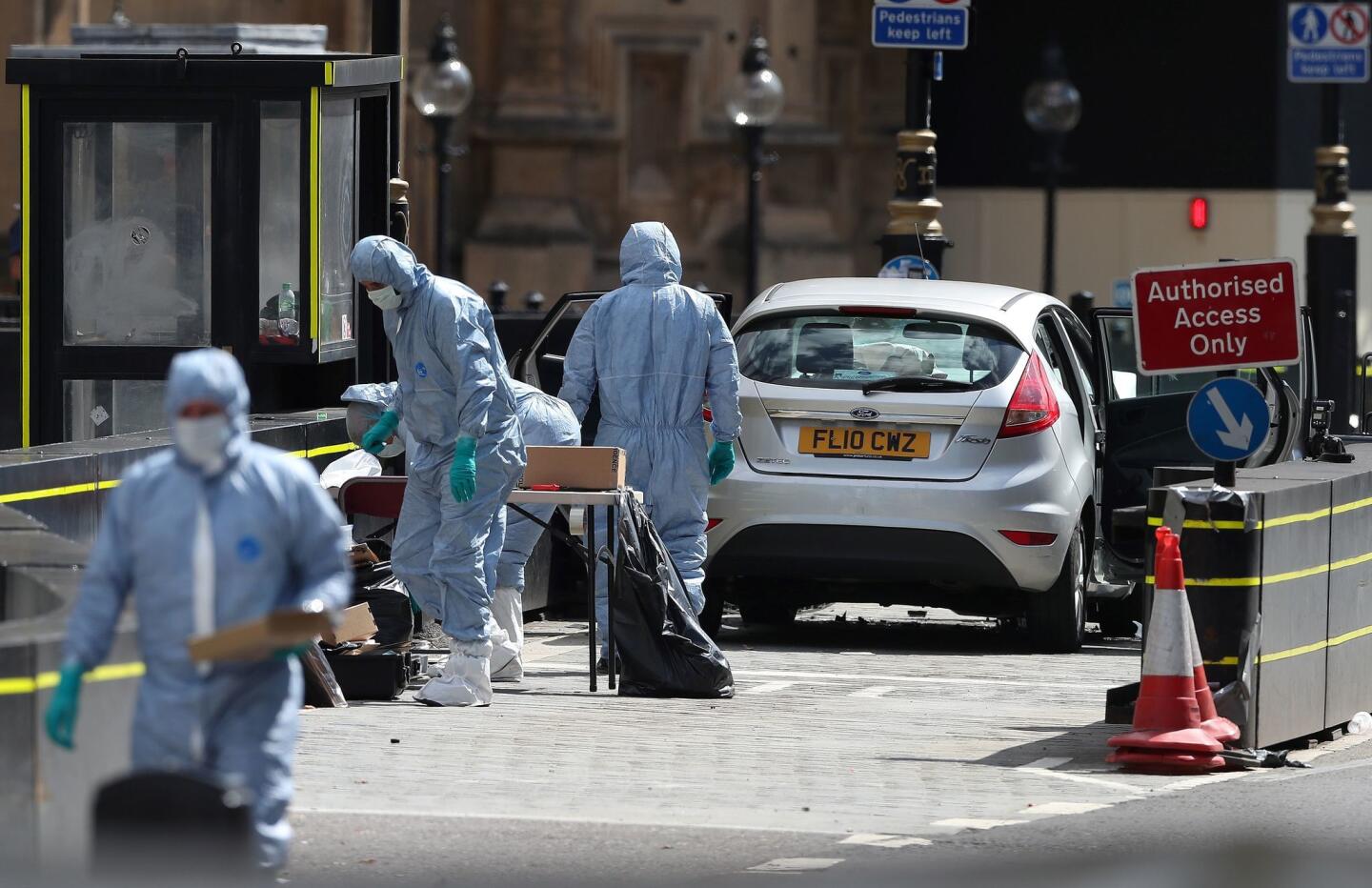 Police forensics officers work around a silver Ford Fiesta that was driven into a barrier at the Houses of Parliament in central London, injuring pedestrians yards from where five people were killed last year.