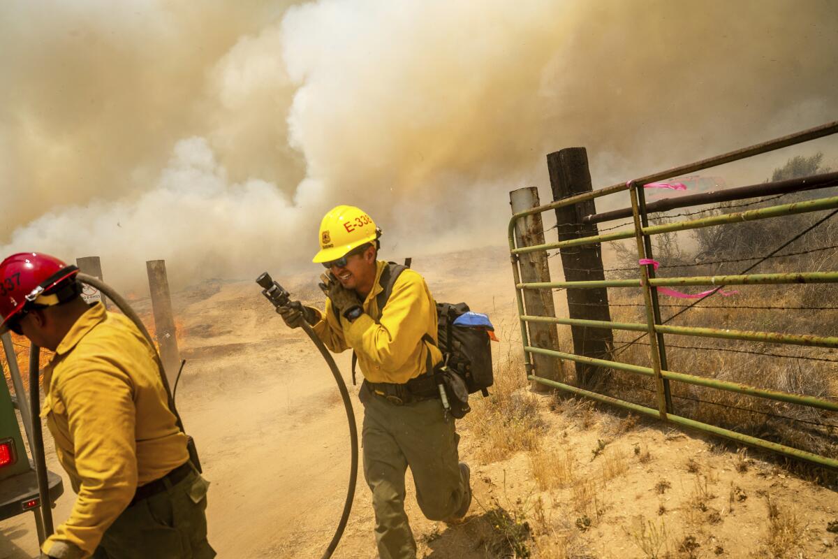 U.S. Forest Service firefighter Alan Gudino shields his face while battling the Madre Fire.