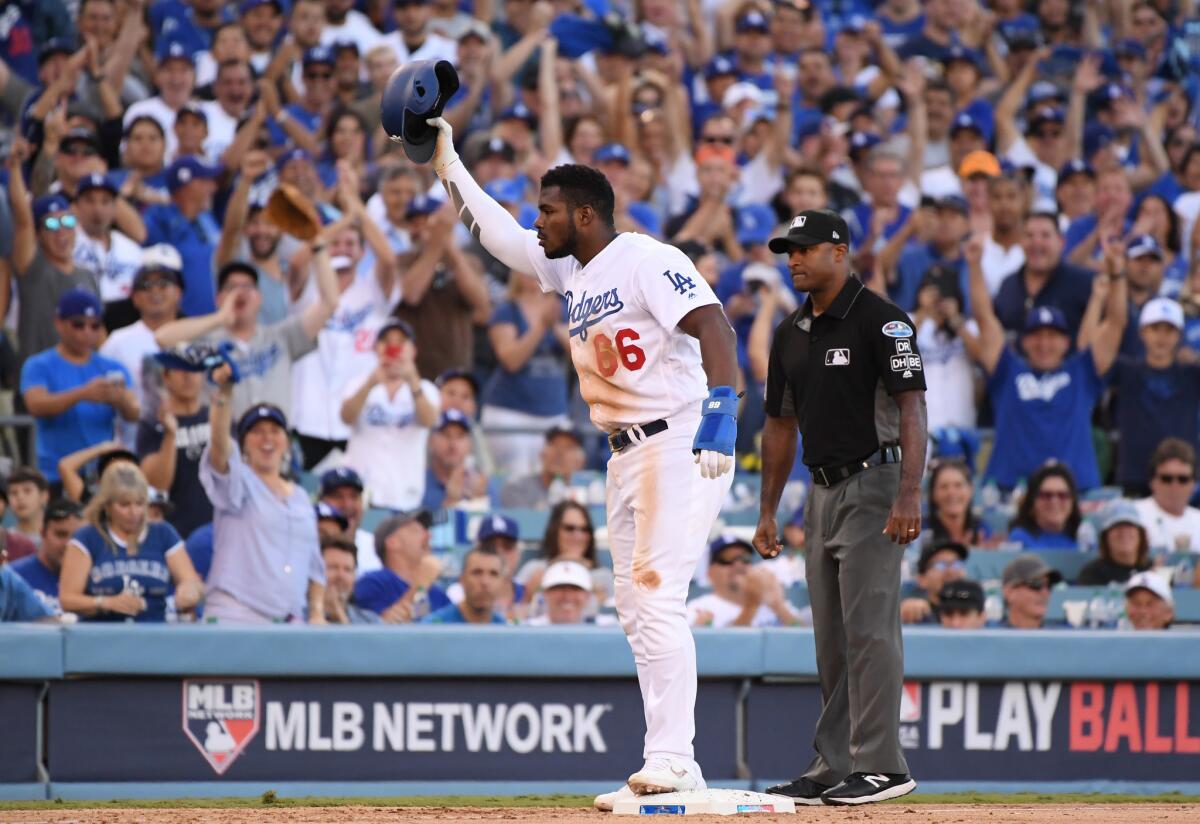 Yasiel Puig #66 of the Los Angeles Dodgers reacts after stealing third base as third base umpire Alan Porter #54 looks on during the eighth inning of Game Five of the National League Championship Series against the Milwaukee Brewers at Dodger Stadium on October 17, 2018 in Los Angeles, California. Puig was sent back to second base after home plate umpire Jim Wolf ruled the batter interfered with the throw to third base.