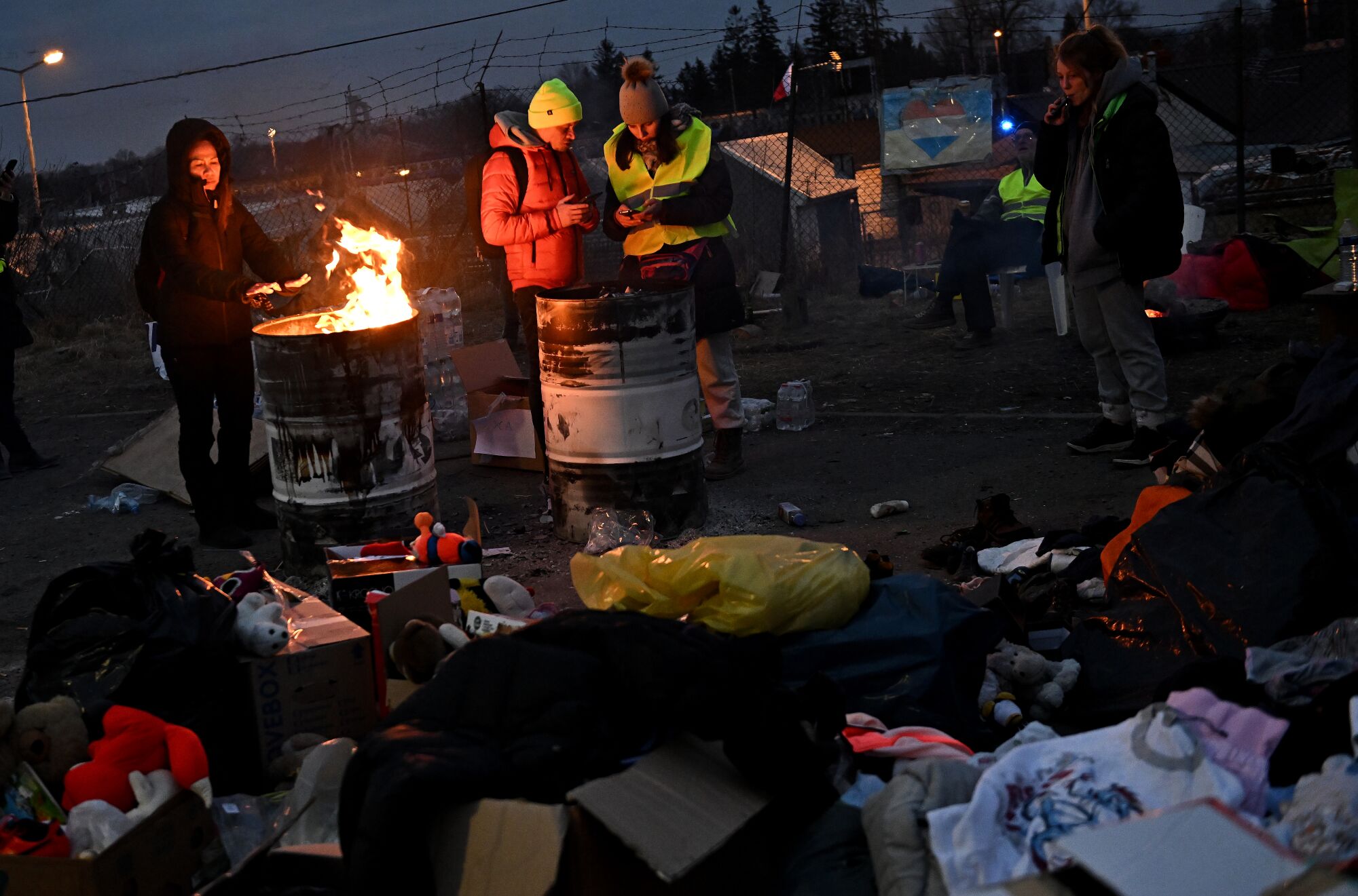 Volunteers try to stay warm next to a donation of clothes for Ukrainian refugees.