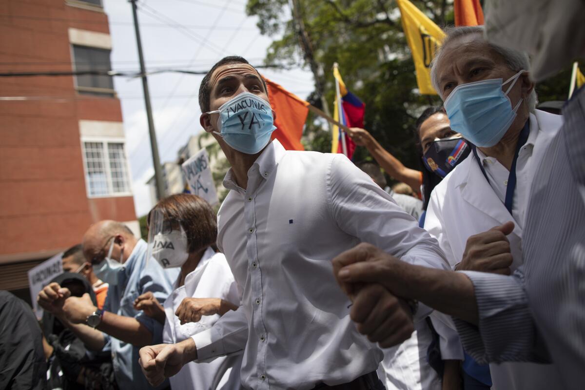 El líder opositor venezolano Juan Guaidó, centro, usa mascarilla al sumarse a una marcha