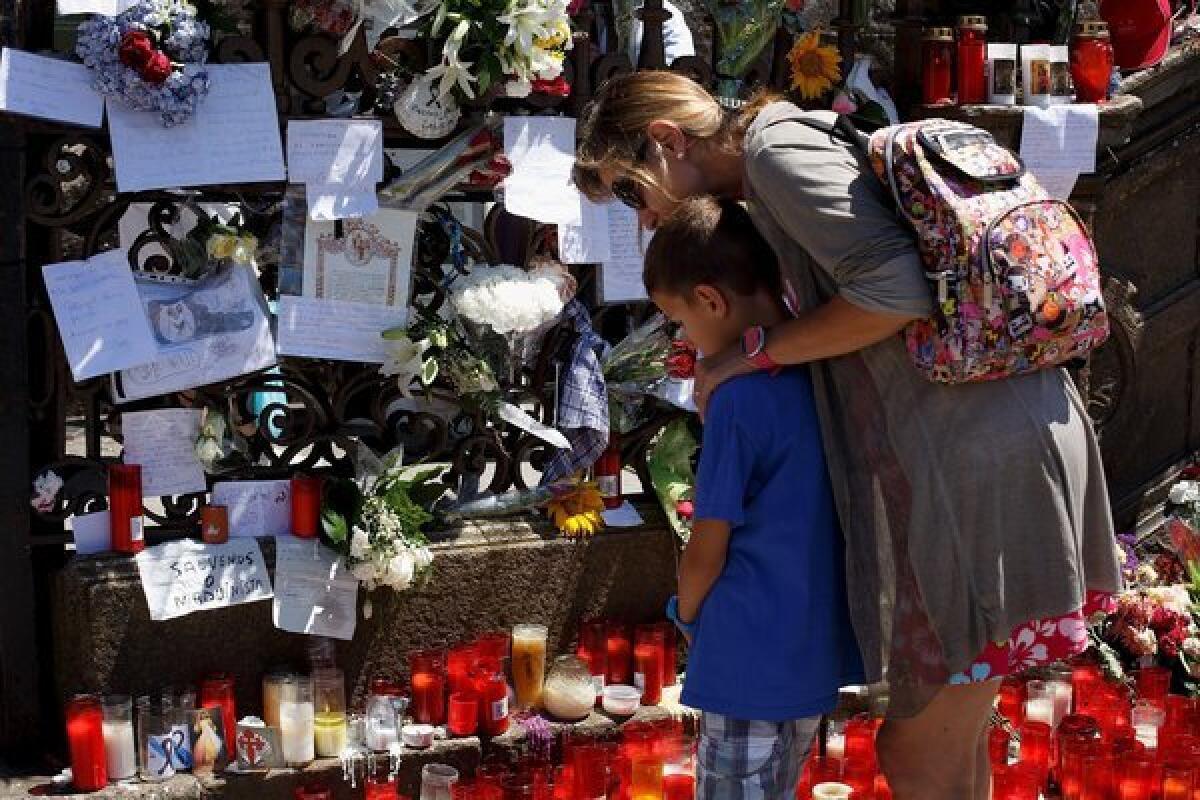At the gate of the cathedral in Santiago de Compostela, Spain, people look at messages, flowers and candles left in memory of the victims of a train derailment.