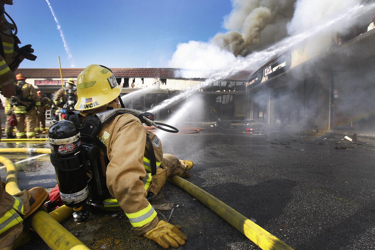 A fireman from Glendale station 23 holds a stream from a line of hose steady on a hot spot at the scene of an intense fire in a strip mall on the corner of Howard Street and Glendale Blvd. in Glendale on Monday, February 10, 2014.