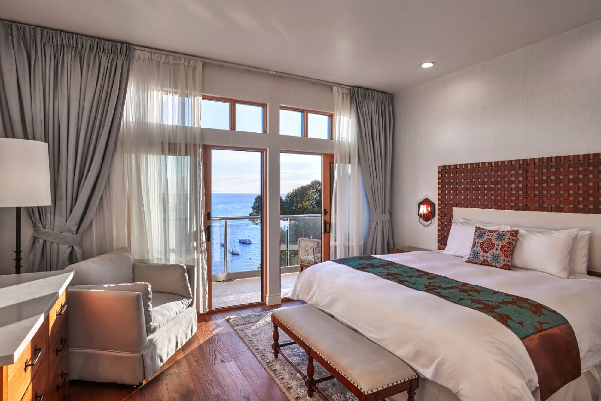 A spacious hotel room with wood floors and a view of the ocean