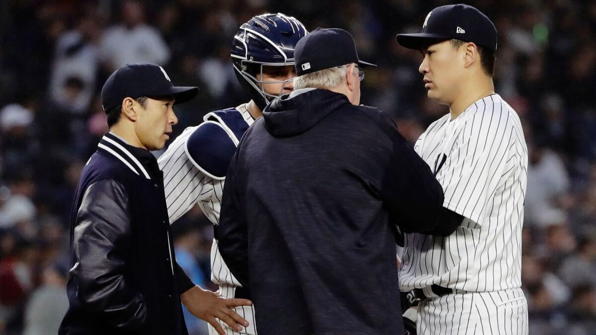New York Yankees pitcher Masahiro Tanaka talks to catcher Gary Sanchez, translator Shingo Horie, left, and pitching coach Larry Rothschild during a game against Boston on Tuesday.