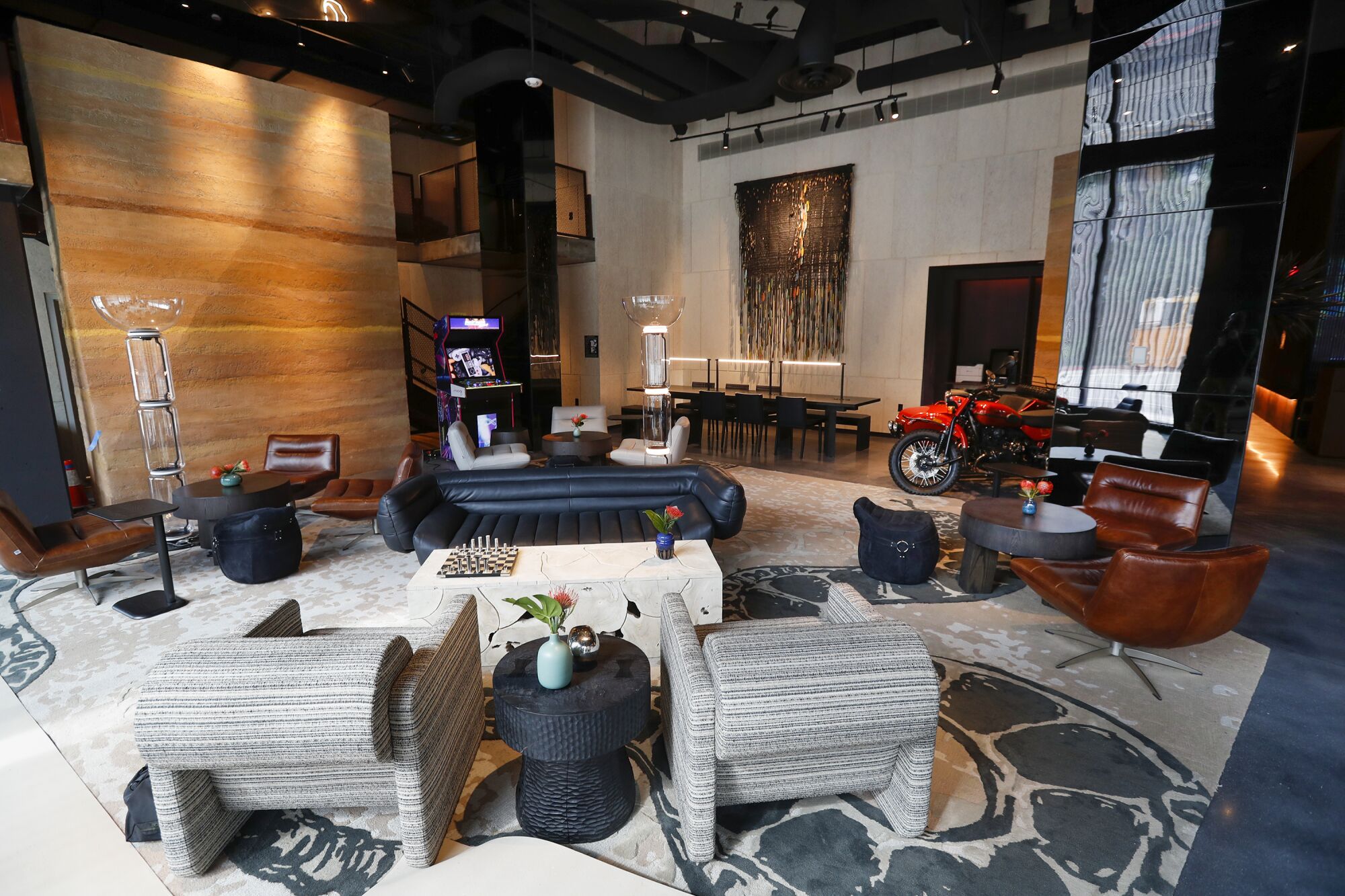 The Moxy lobby has a rammed-earth wall, motorcycle and macrame decoration to evoke a nomadic, desert sensibility.