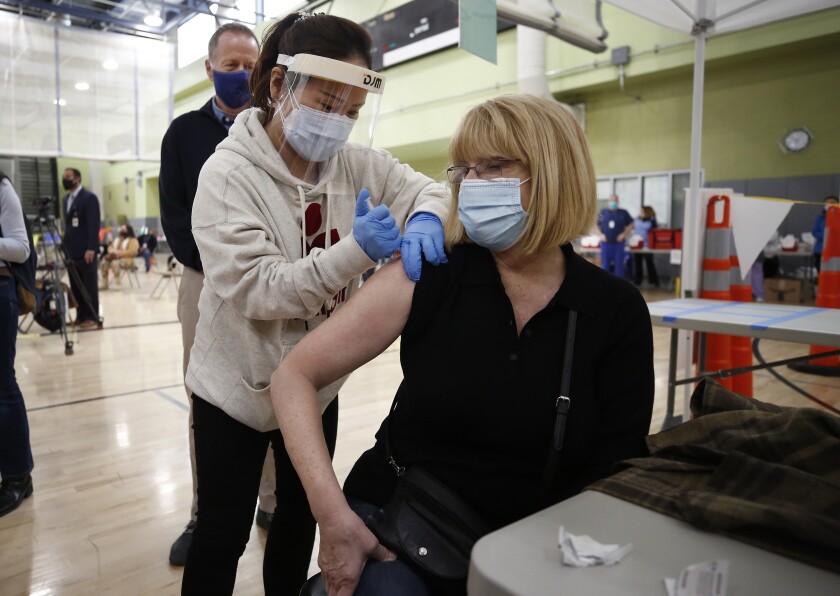A teacher receives a COVID-19 vaccine shot