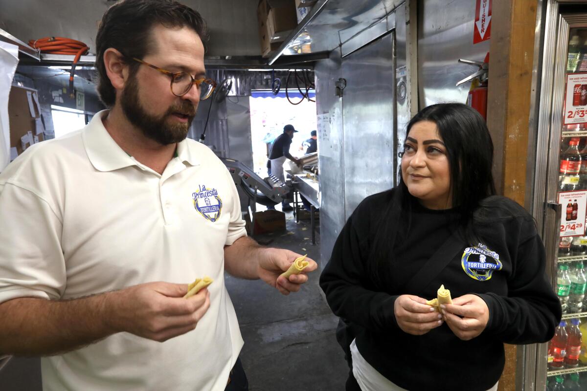 A man and a woman meet in an industrial kitchen.