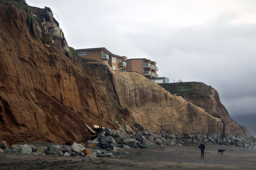 PACIFICA, CALIFORNIA--JAN. 20, 2019--On Pacifica Esplanade Dog Beach, the remains of an apartment building that fell off of the cliffs can be seen along with one still standing. Most of the building was removed, but some debris remains on the beach. The town of Pacifica, just south of San Francisco, is ground zero for the issue of coastal erosion. On Jan. 20-21, the combination of ocean surge and a king tide caused high waves. Some homes and apartment building have already been lost to the forces of nature. (Carolyn Cole/Los Angeles Times)
