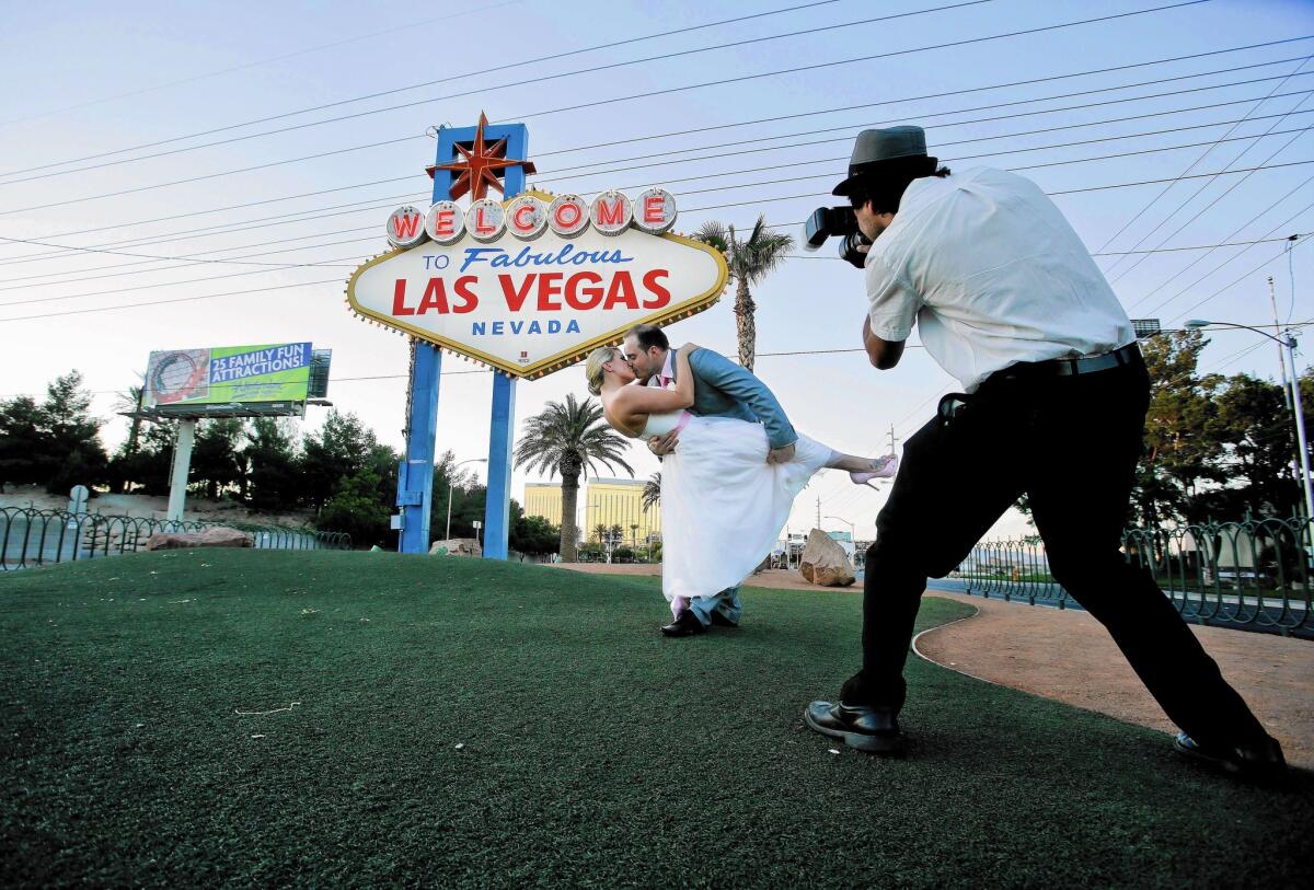 Katy Garrett and husband Stuart strike a pose near a Vegas welcome sign in 2012. 