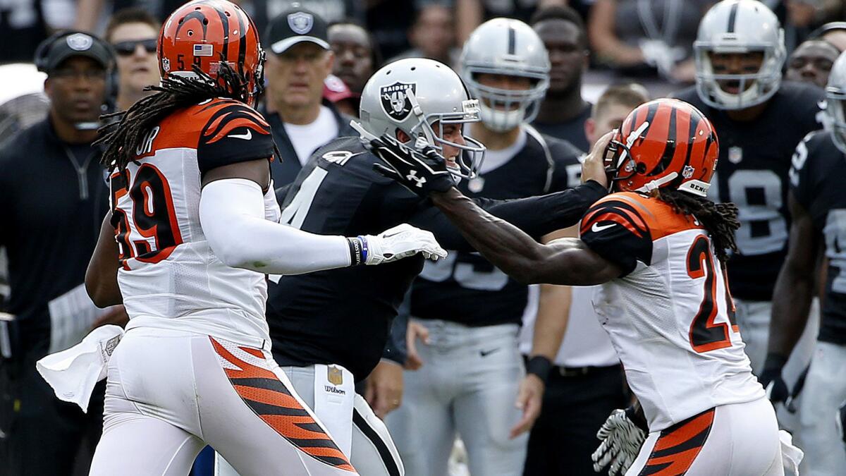 Raiders quarterback Derek Carr (4) injures his hand as he stiff-arms Bengals cornerback Adam Jones as he scrambled during the first half of their game Sunday in Oakland.