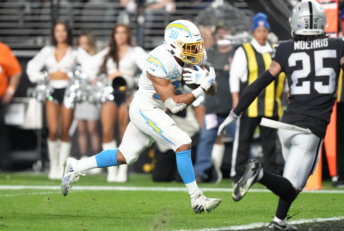 The Chargers' Austin Ekeler (30) runs for a touchdown in the first half as the Raiders Tre'von Moehrig pursues too late.
