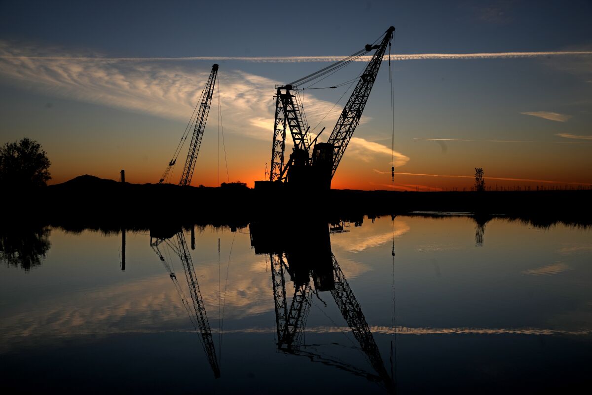 Cranes are reflected in water.