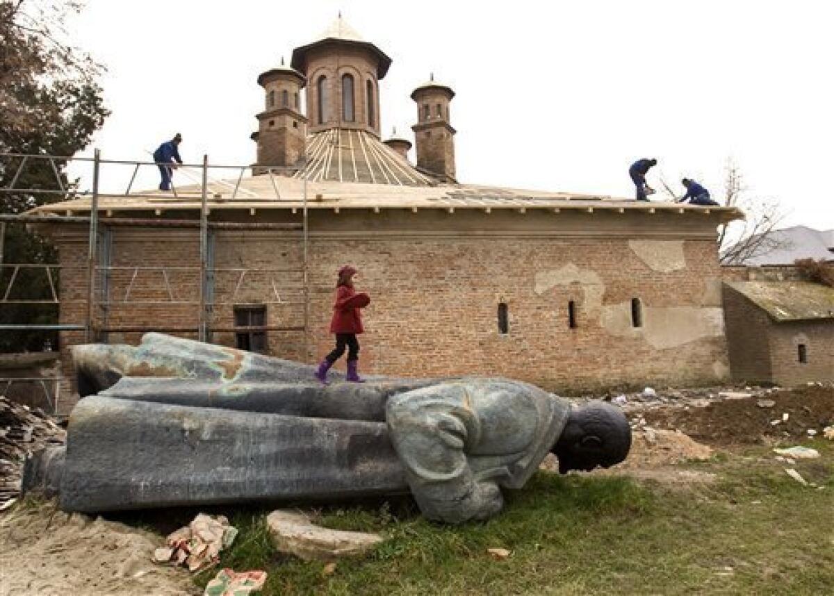 In this picture taken on Dec. 11, 2009, a child walks on the statue of Vladimir Lenin, abandoned in the backyard of the Mogosoaia Palace, Romania, after being removed from a Bucharest square in 1990 as work to restore the church of the Mogosoaia Palace takes place behind. This week Romanians commemorate 20 years since communist dictator fled Bucharest during a popular uprising on Dec. 22, 1989, after ruling Romania for 25 years. Ceausescu was executed together with his wife Elena on Dec. 25, 1989.More than a thousand people are reported to have lost their lives during the Romanian revolution.(AP Photo/Vadim Ghirda)