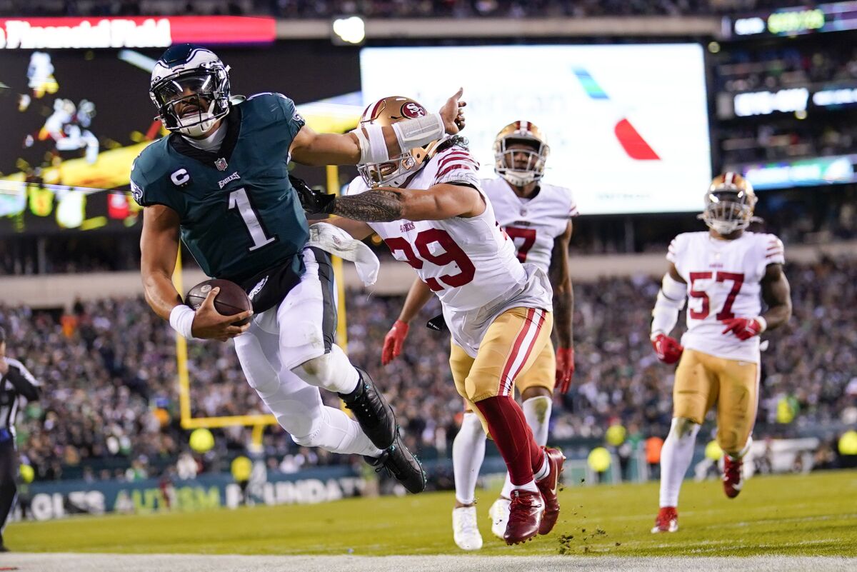 Philadelphia Eagles quarterback Jalen Hurts is pushed out of bounds by San Francisco 49ers safety Talanoa Hufanga.
