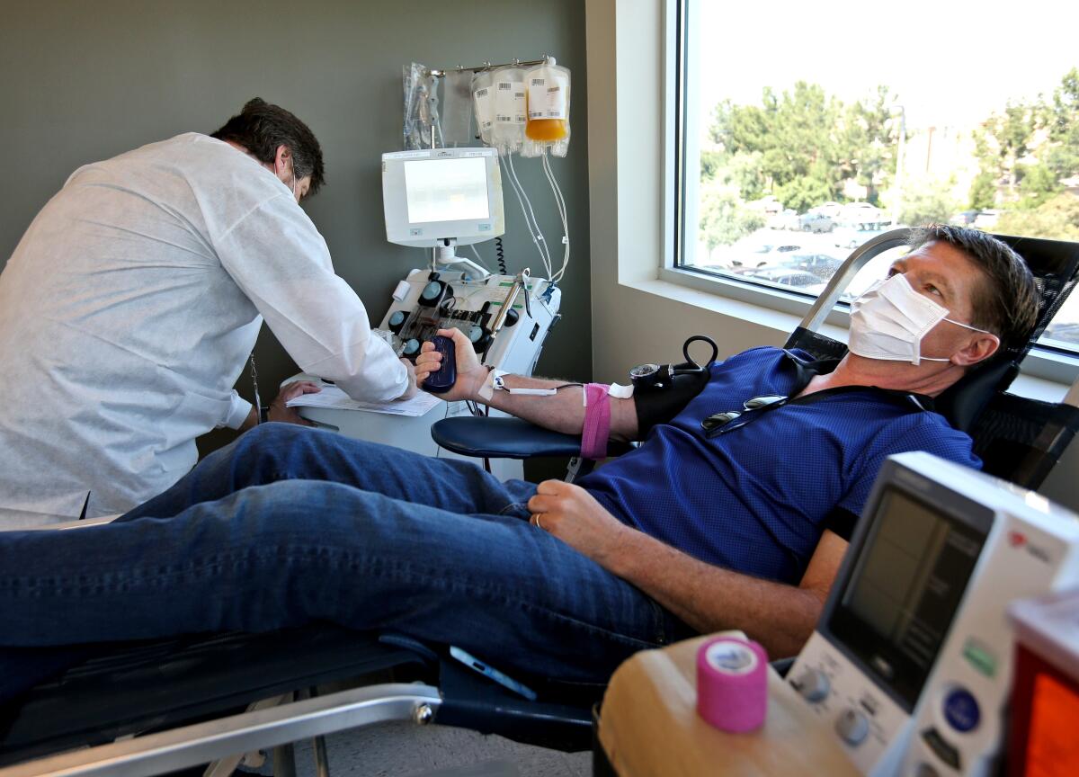 Glenn Walcott, 51 of Newport Beach, right, donates 840ml of plasma to San Diego Blood Bank during a 45-minute session at Hoag Health Center in Irvine Tuesday. Walcott's blood tested positive for SARS-CoV2 antibodies after he contracted the virus in March.