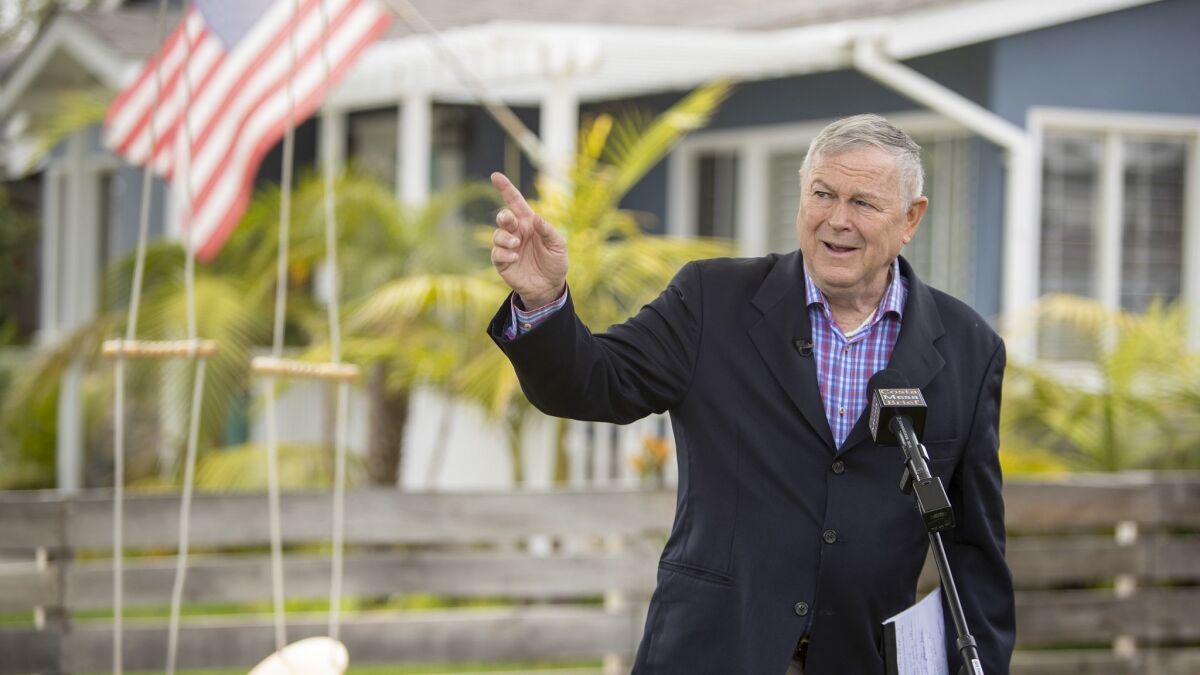 Rep. Dana Rohrabacher points to a commercial aircraft that can be heard leaving John Wayne Airport during a news conference at his home in Costa Mesa on April 23.