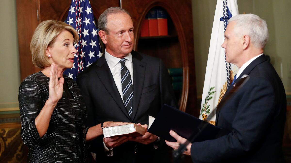 El vicepresidente Mike Pence, a la derecha, toma el juramento a la nueva secretaria de educación, Betsy DeVos. A ellos se les une Dick DeVos, esposo de la funcionaria. (Pablo Martínez Monsivais)