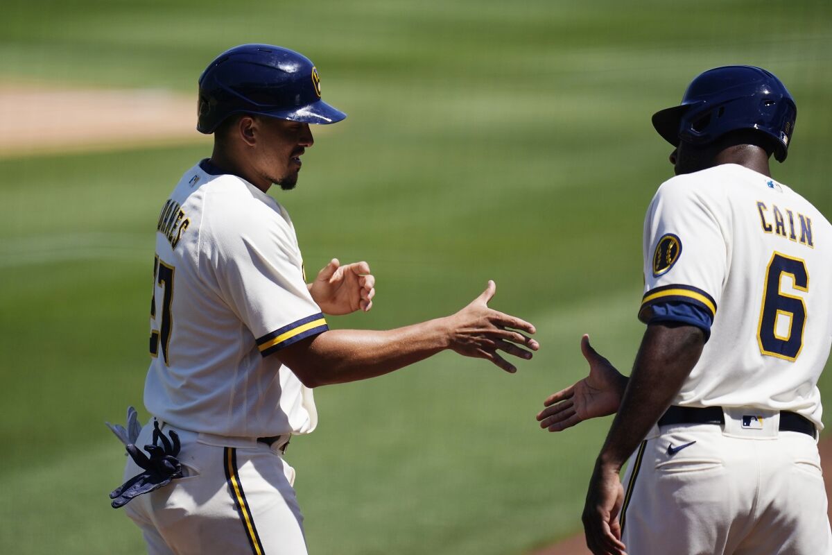 Milwaukee Brewers' Willy Adames, left, and Lorenzo Cain (6) celebrate their runs scored against the Kansas City Royals during the third inning of a spring training baseball game Tuesday, April 5, 2022, in Phoenix. (AP Photo/Ross D. Franklin)