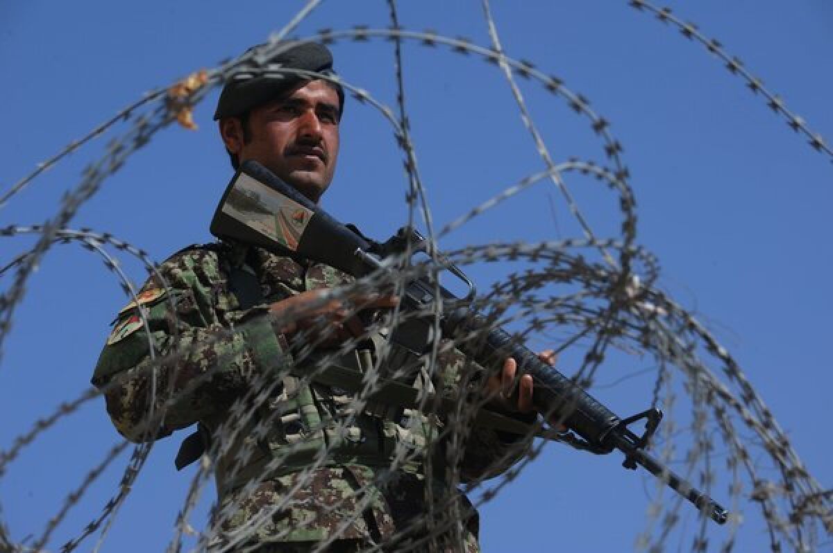 An Afghan soldier stands guard as potential army recruits gather in Herat last month.