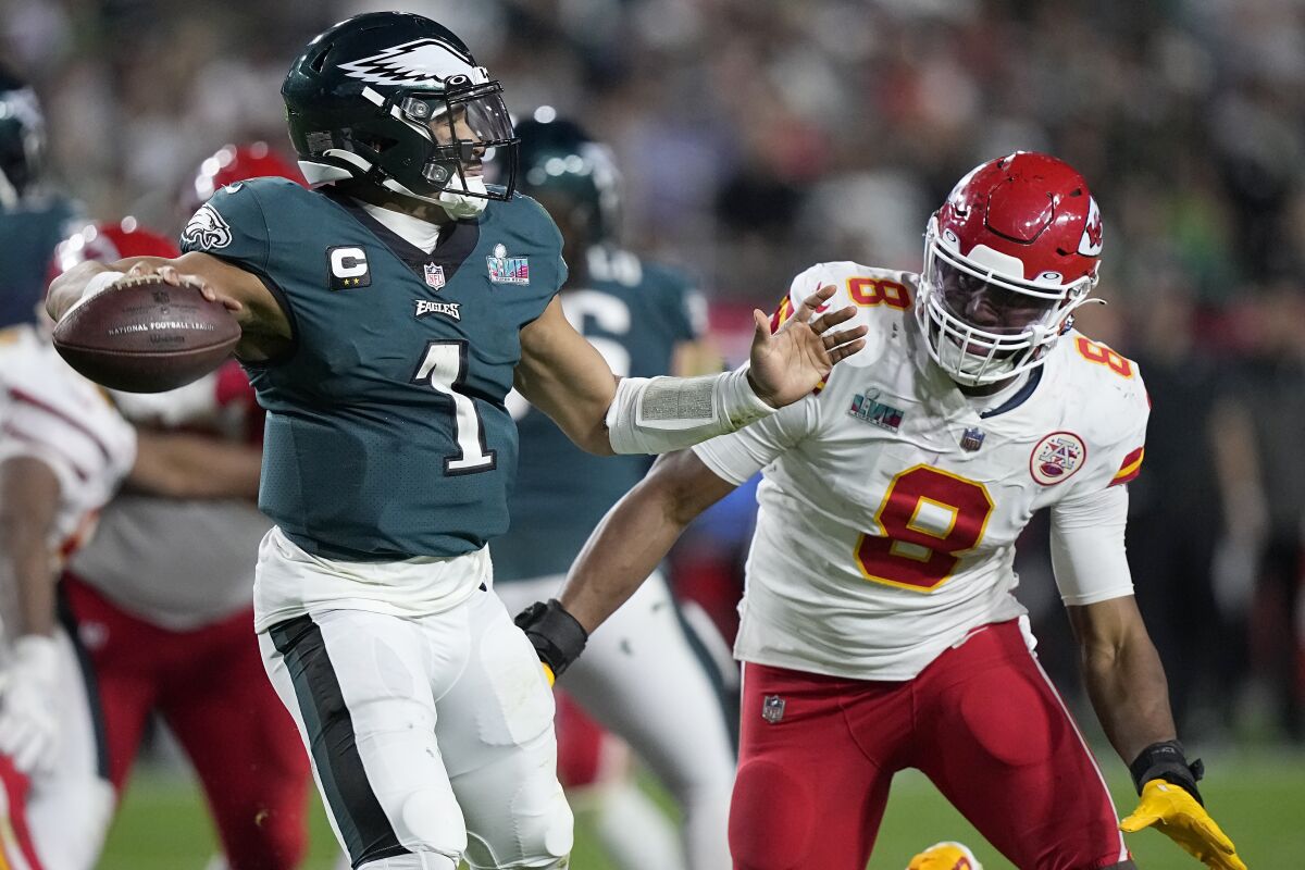 Philadelphia Eagles quarterback Jalen Hurts passes under pressure by Kansas City Chiefs defensive end Carlos Dunlap.