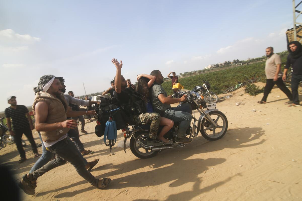 Palestinians transport a captured Israeli civilian on a motorcycle.