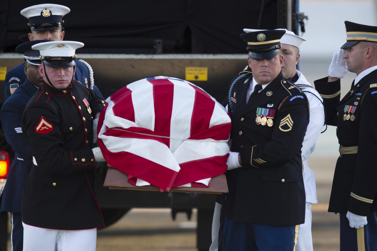 An armed forces color guard carries a casket, draped with a U.S. flag, at San Francisco International Airport.