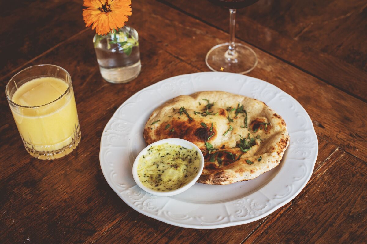 Naan with butter and a cocktail on a wooden table.
