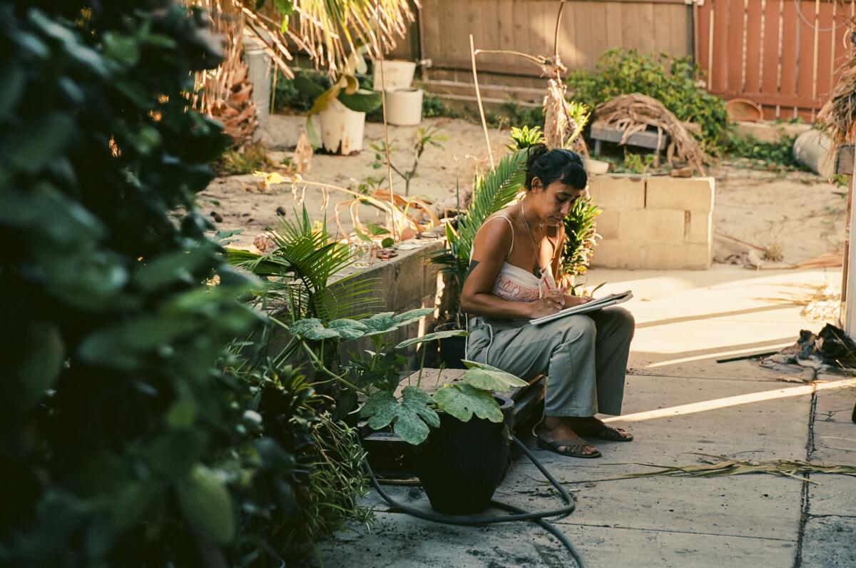 Maria Maea sits on a concrete step and makes notes in her family's patio.