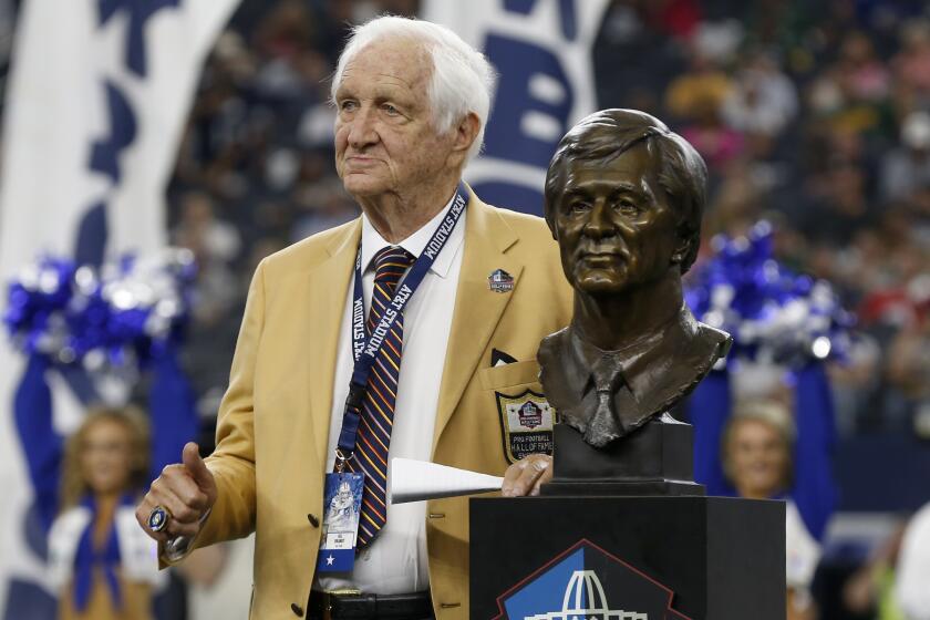 Pro Football Hall off Fame inductee Gil Brandt poses with his bust during a ceremony.
